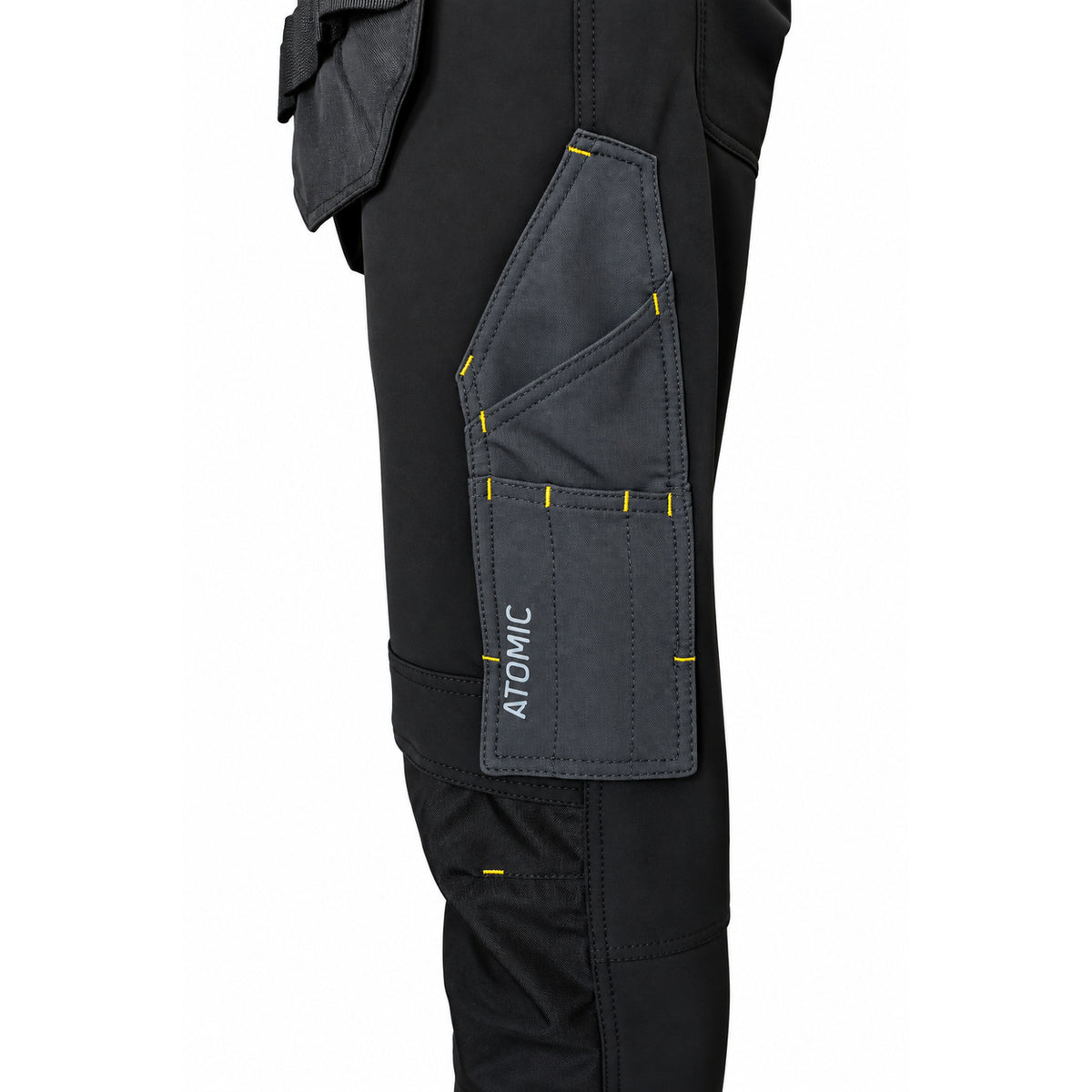 Close-up of ATOMIC work trouser rule pocket with multiple tool compartments and reinforced yellow stitching.